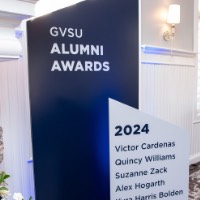 Large blue and white sign with alumni award recipient names